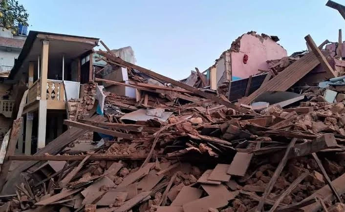 India Aid to Nepal: Indian and Nepal flags with damaged earthquake-hit buildings in the background representing reconstruction support.