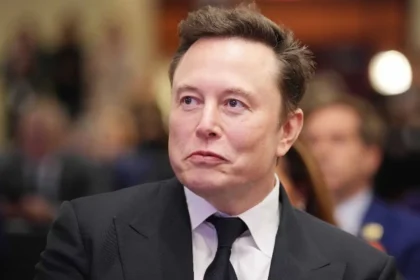Elon Musk Net Worth speaking at an event as SpaceX shares surge following its Nasdaq listing, pushing his net worth above $1 trillion.